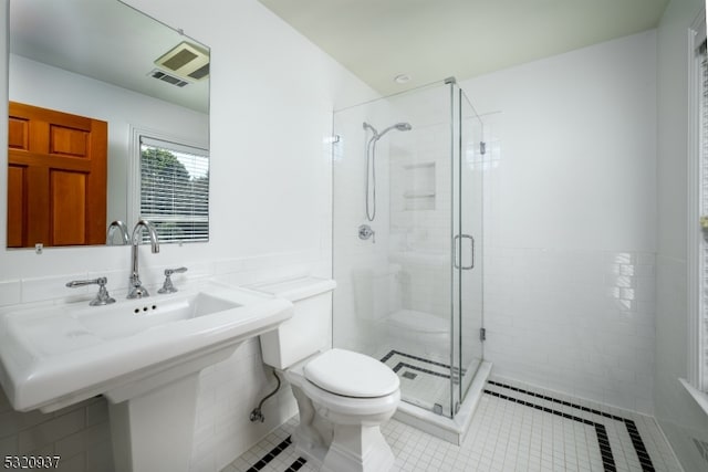 bathroom featuring tile patterned flooring, toilet, and a shower with door