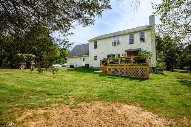 rear view of property with a yard, central air condition unit, and a wooden deck