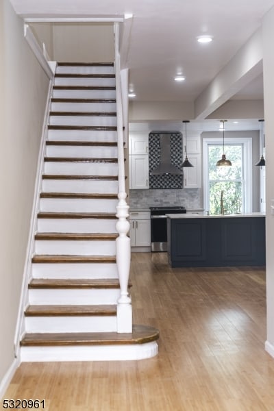 stairs featuring hardwood / wood-style flooring and sink