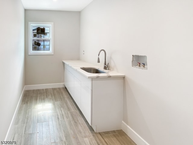 laundry room with cabinets, sink, washer hookup, and light wood-type flooring