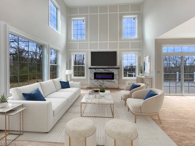 living room featuring a towering ceiling, a fireplace, and plenty of natural light