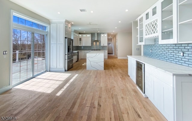 kitchen with decorative backsplash, white cabinets, stainless steel refrigerator with ice dispenser, and beverage cooler