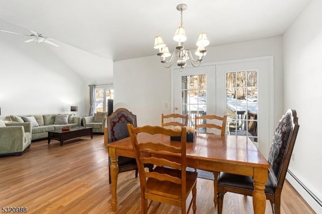 dining space featuring hardwood / wood-style floors, ceiling fan with notable chandelier, a baseboard radiator, and vaulted ceiling