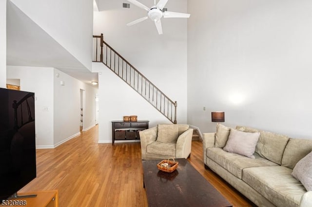 living room featuring ceiling fan, a towering ceiling, and wood-type flooring