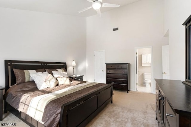 carpeted bedroom featuring a high ceiling, ensuite bathroom, and ceiling fan