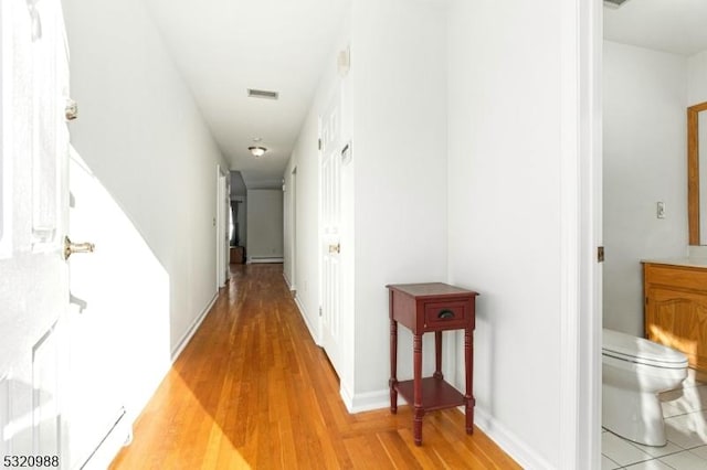 hall featuring baseboard heating and light hardwood / wood-style floors