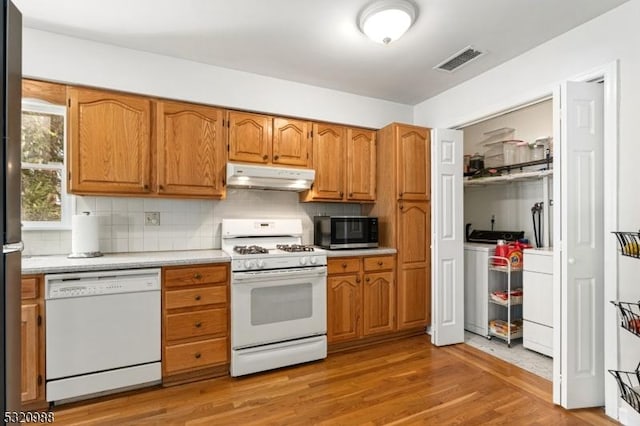 kitchen featuring hardwood / wood-style flooring, separate washer and dryer, white appliances, and decorative backsplash