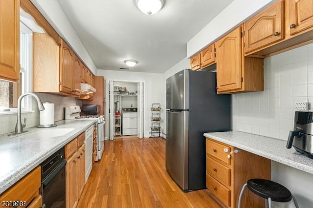 kitchen with stainless steel refrigerator, tasteful backsplash, sink, white range with gas cooktop, and light hardwood / wood-style flooring