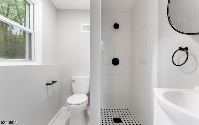 bathroom featuring toilet, sink, and tiled shower