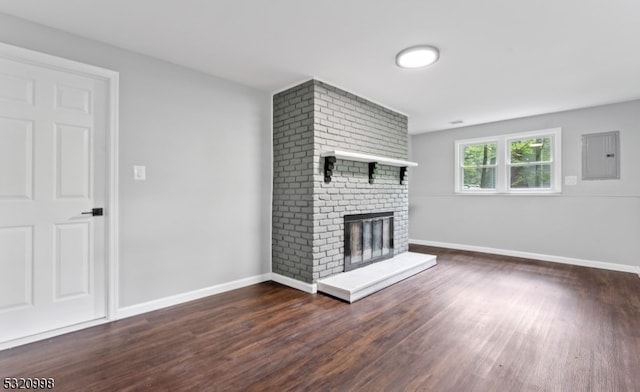 unfurnished living room with electric panel, a brick fireplace, and dark hardwood / wood-style floors