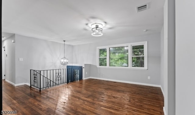 spare room featuring a chandelier and dark hardwood / wood-style flooring