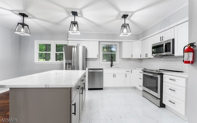 kitchen featuring white cabinetry, stainless steel appliances, and decorative light fixtures