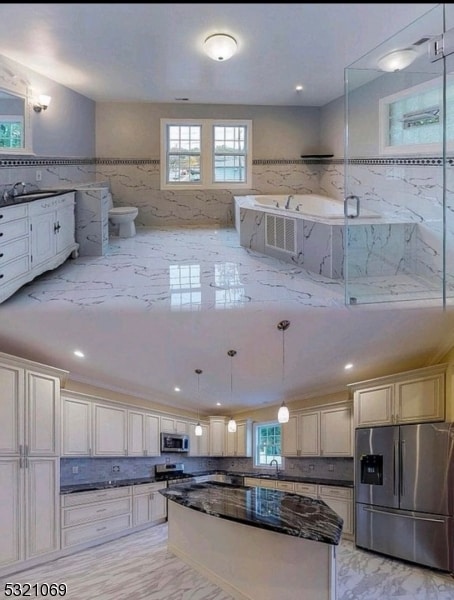 kitchen featuring stainless steel appliances, a wealth of natural light, dark stone counters, and decorative light fixtures