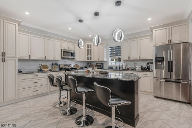 kitchen with a kitchen island, appliances with stainless steel finishes, pendant lighting, a breakfast bar, and dark stone countertops