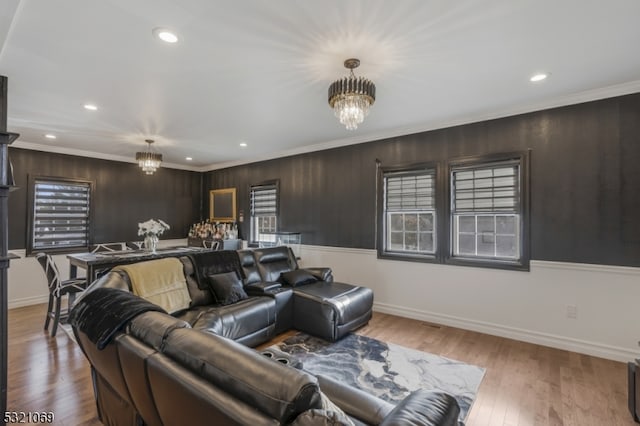 living room featuring wood walls, a chandelier, ornamental molding, and light hardwood / wood-style flooring