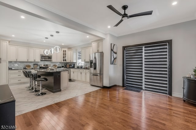 kitchen with stainless steel appliances, a kitchen breakfast bar, a kitchen island, light hardwood / wood-style flooring, and decorative light fixtures