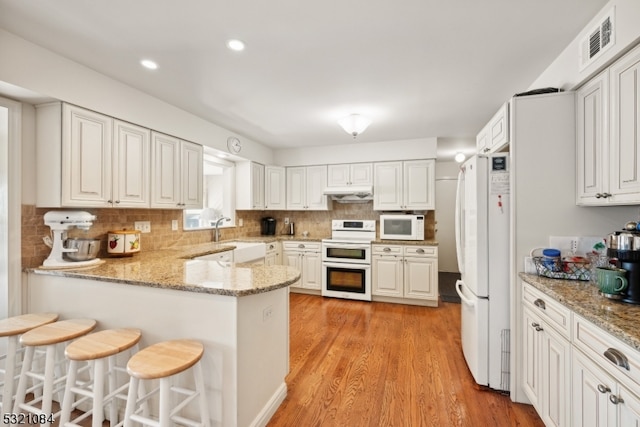 kitchen featuring white appliances, light wood-type flooring, white cabinetry, and kitchen peninsula