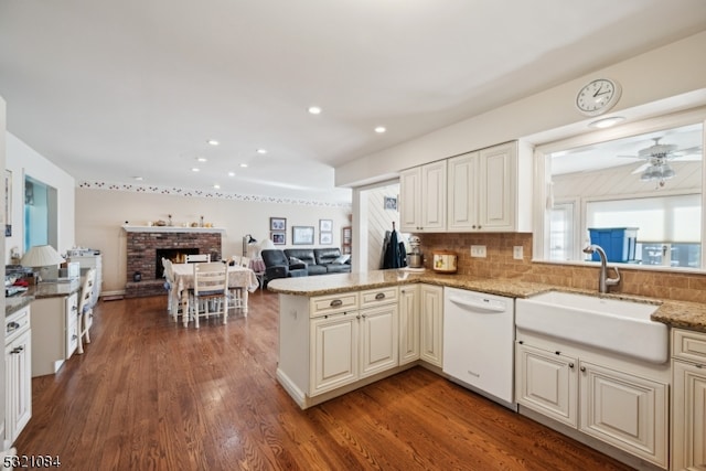 kitchen featuring dishwasher, kitchen peninsula, a healthy amount of sunlight, and dark hardwood / wood-style flooring