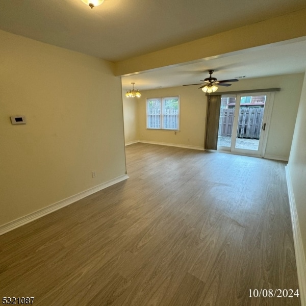 spare room with hardwood / wood-style flooring and ceiling fan with notable chandelier