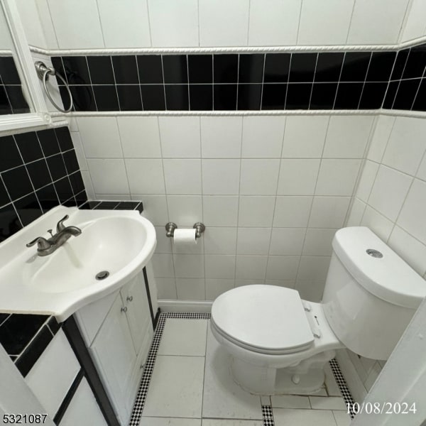 bathroom featuring vanity, toilet, tile walls, and tile patterned flooring