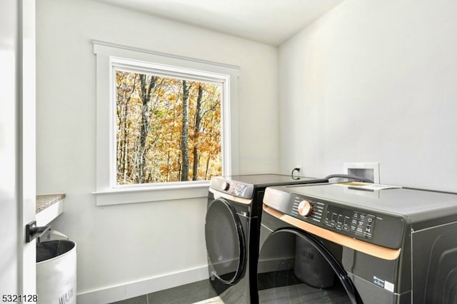 clothes washing area with washing machine and dryer and dark tile patterned floors