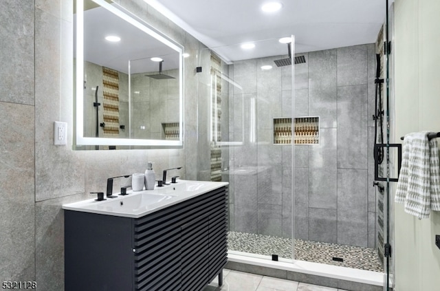 bathroom with tile walls, vanity, a shower with shower door, and tile patterned floors