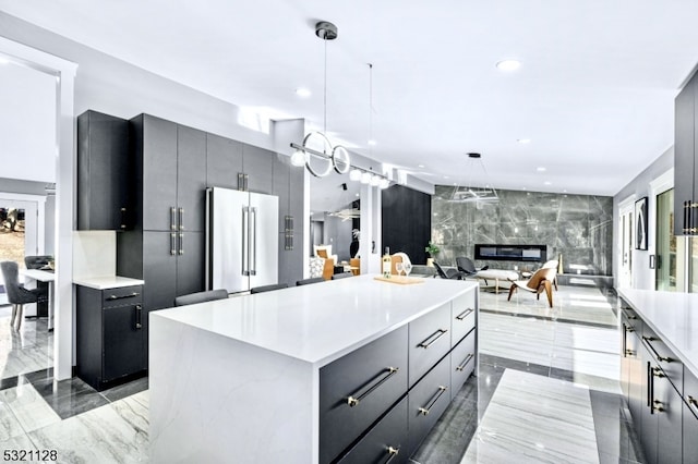 kitchen featuring high end refrigerator, a kitchen island, tile walls, a fireplace, and pendant lighting