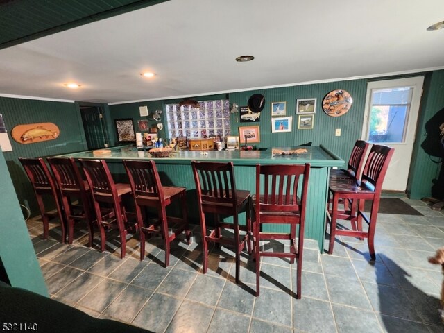 bar with ornamental molding and tile patterned floors