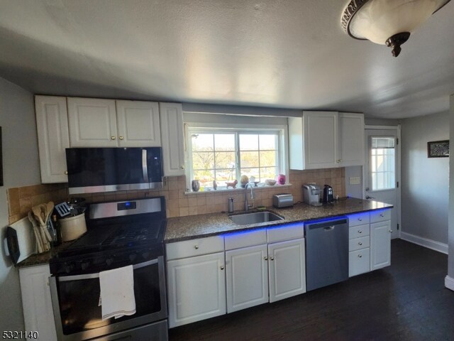 kitchen featuring tasteful backsplash, white cabinetry, appliances with stainless steel finishes, and sink