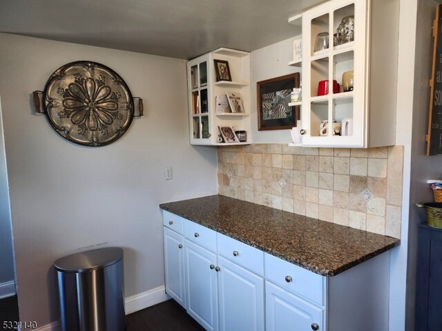 kitchen with white cabinets, dark stone countertops, and decorative backsplash