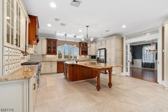 kitchen featuring light stone countertops, stainless steel appliances, a center island with sink, hanging light fixtures, and a breakfast bar area