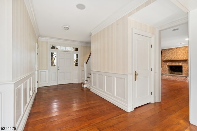 foyer entrance featuring hardwood / wood-style floors, ornamental molding, and a fireplace