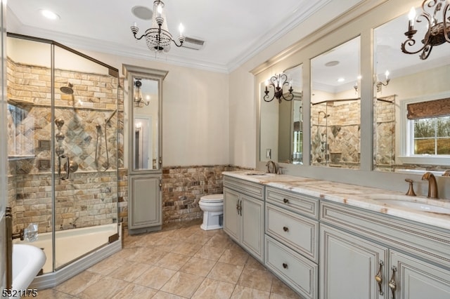 bathroom featuring crown molding, toilet, a shower with door, vanity, and tile walls