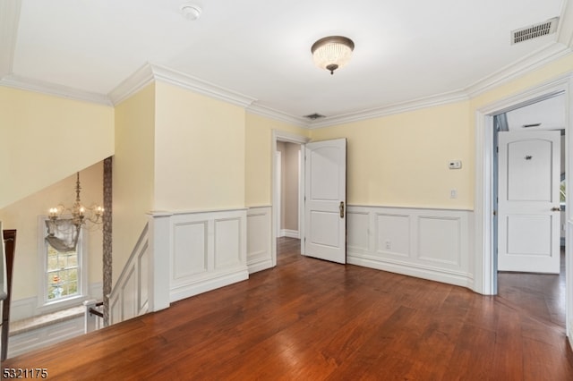 spare room featuring an inviting chandelier, dark wood-type flooring, and crown molding