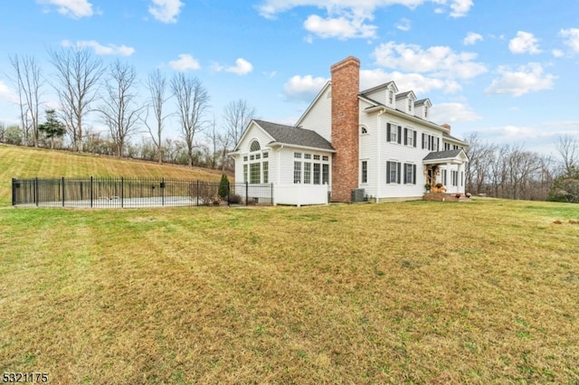 rear view of property featuring a lawn, central AC, and a sunroom