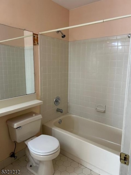 bathroom featuring toilet, tiled shower / bath combo, and tile patterned flooring