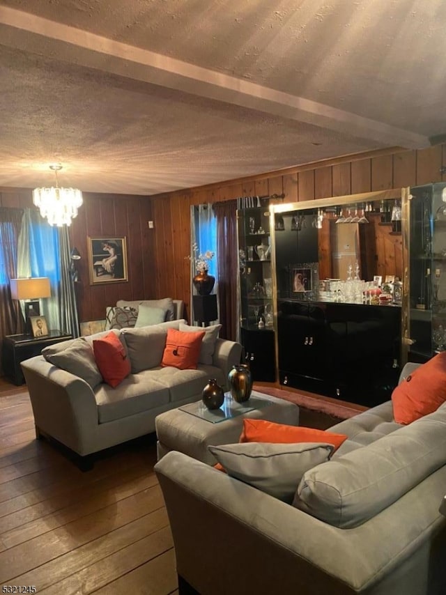 living room featuring beamed ceiling, a notable chandelier, and wood-type flooring