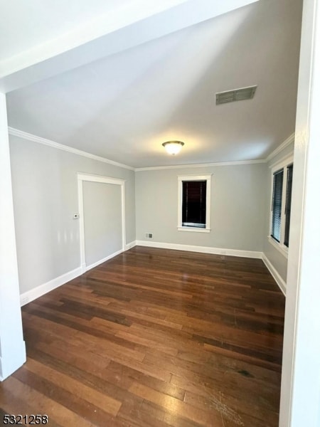 spare room featuring ornamental molding and dark wood-type flooring