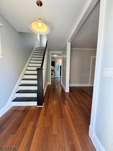 staircase with wood-type flooring and ornamental molding