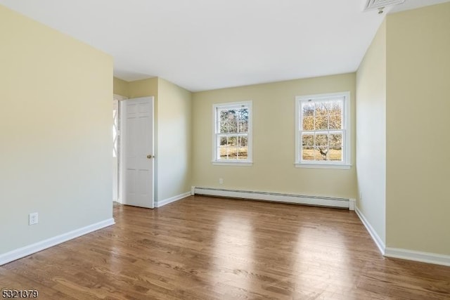 unfurnished room with baseboard heating and wood-type flooring