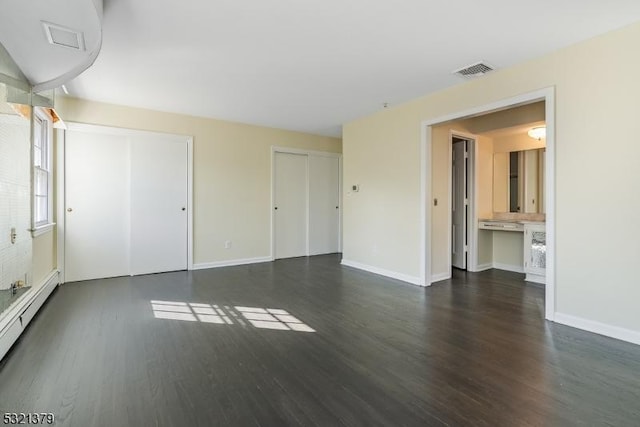 spare room with dark wood-type flooring and baseboard heating