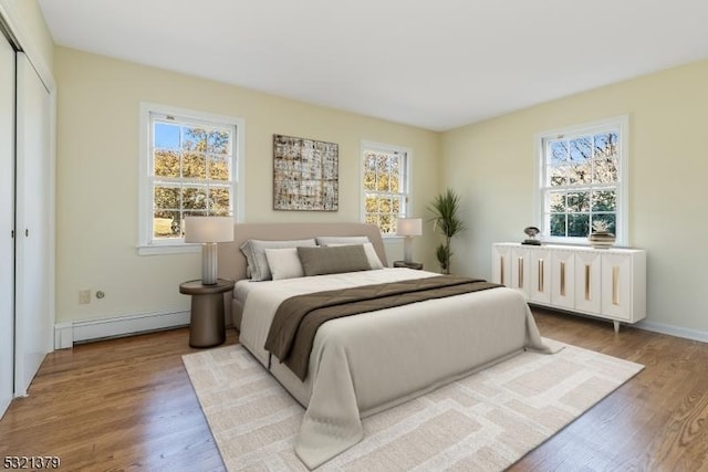 bedroom with hardwood / wood-style flooring, a baseboard radiator, and a closet