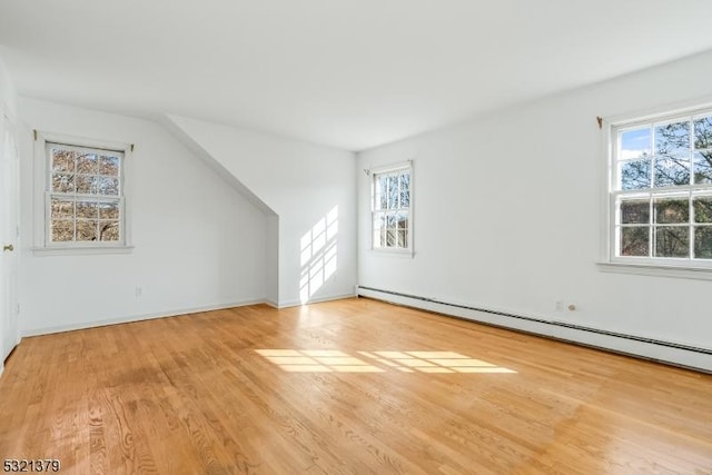 additional living space with light hardwood / wood-style floors, plenty of natural light, and a baseboard radiator