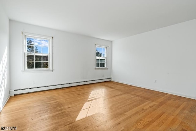 spare room featuring a baseboard heating unit and light wood-type flooring