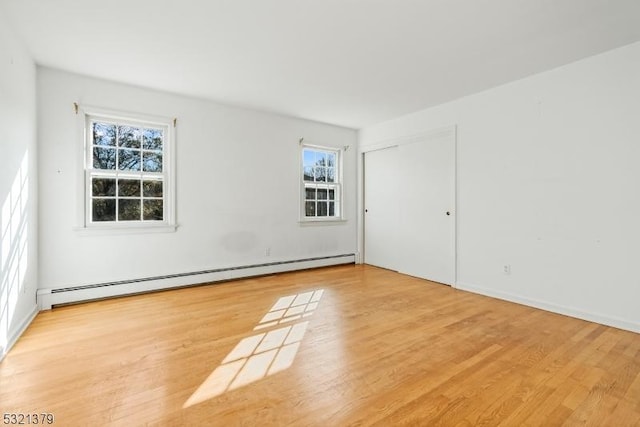 empty room with a baseboard heating unit and light hardwood / wood-style floors