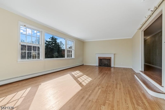 unfurnished living room featuring baseboard heating, a healthy amount of sunlight, light hardwood / wood-style floors, and crown molding