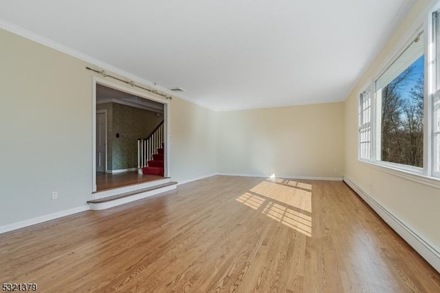 unfurnished room with a baseboard heating unit, ornamental molding, and light wood-type flooring