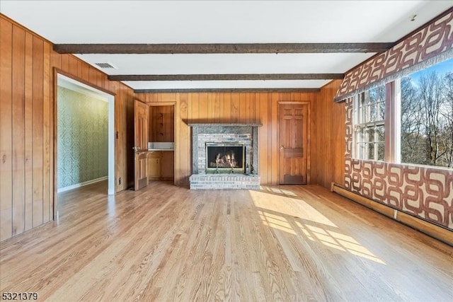 unfurnished living room with light wood-type flooring, a fireplace, beam ceiling, and a baseboard radiator