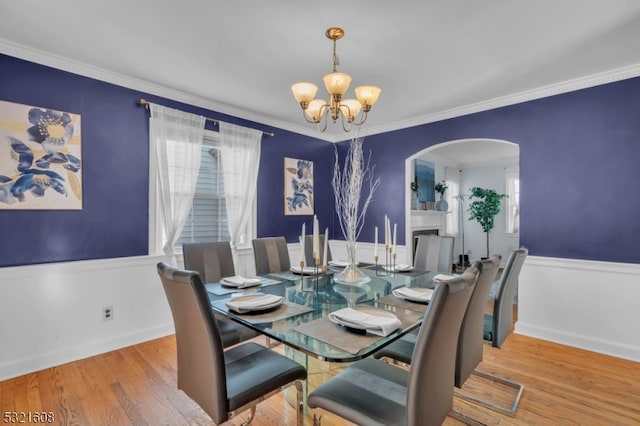 dining room with ornamental molding, an inviting chandelier, and hardwood / wood-style floors