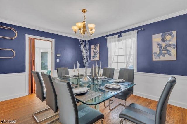 dining space with ornamental molding, hardwood / wood-style floors, and a chandelier